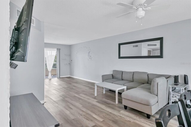 living room with a textured ceiling, ceiling fan, and light hardwood / wood-style floors