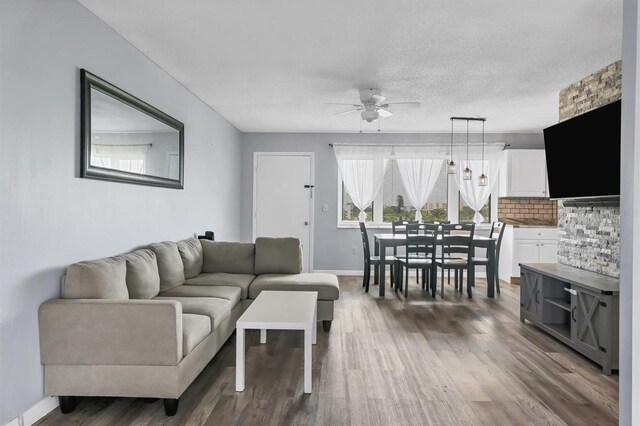 living room with ceiling fan, dark hardwood / wood-style floors, and a textured ceiling