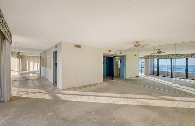 spare room featuring ceiling fan, light carpet, and a water view