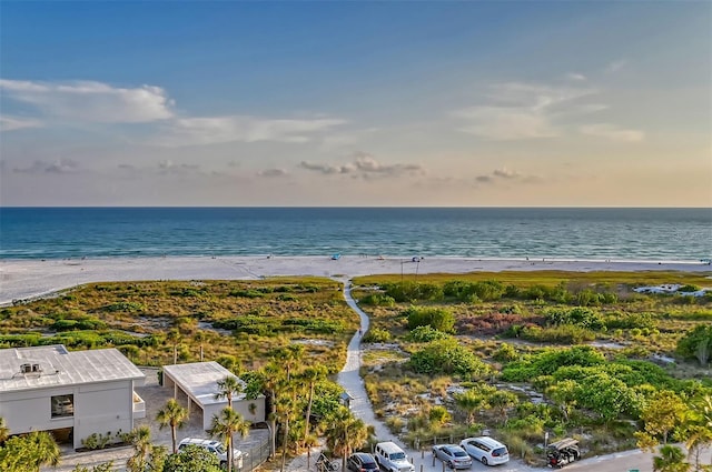 aerial view at dusk featuring a water view and a view of the beach