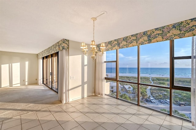 empty room featuring light tile patterned flooring, a wealth of natural light, and a water view