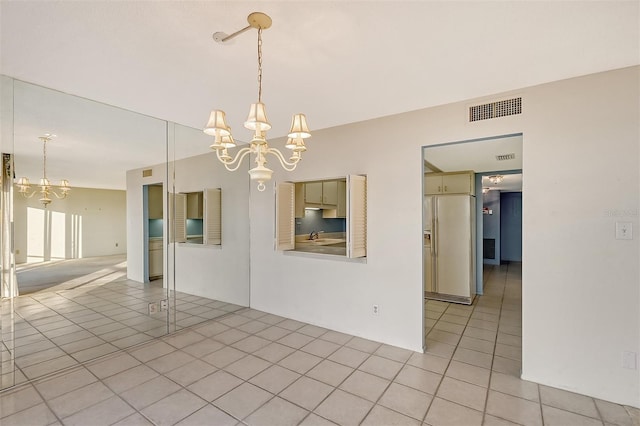 unfurnished dining area featuring light tile patterned flooring and a chandelier