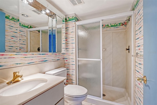 bathroom featuring toilet, vanity, and a shower with shower door