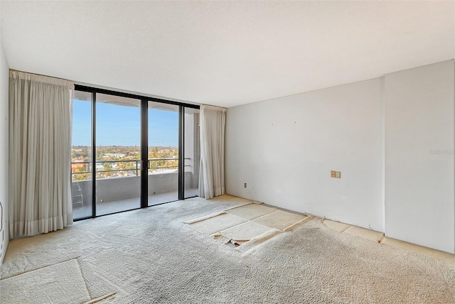 spare room with a wall of windows, french doors, and carpet flooring