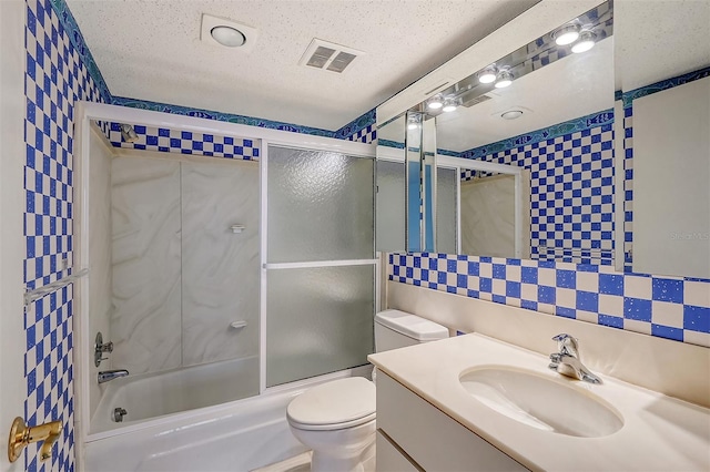 full bathroom with a textured ceiling, vanity, backsplash, toilet, and combined bath / shower with glass door