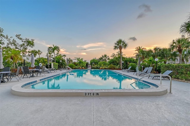 pool at dusk featuring a patio