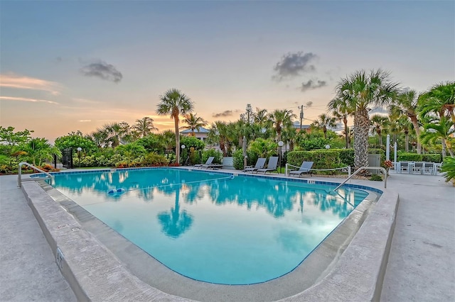 pool at dusk featuring a patio