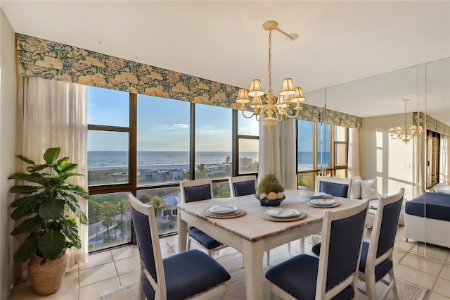 dining space with light tile patterned floors, a water view, a beach view, and a notable chandelier