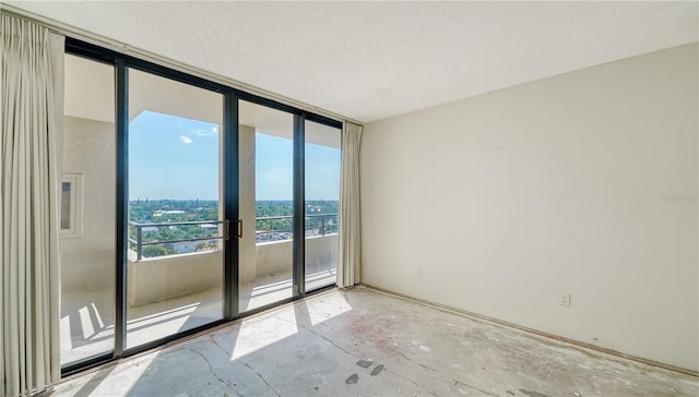 empty room with a textured ceiling, floor to ceiling windows, and french doors