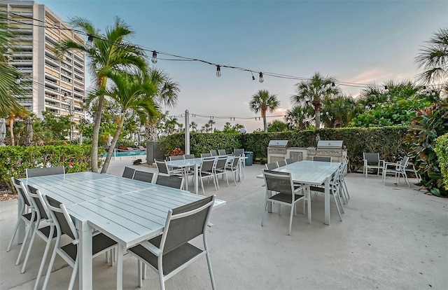 patio terrace at dusk featuring a grill, area for grilling, and a pool