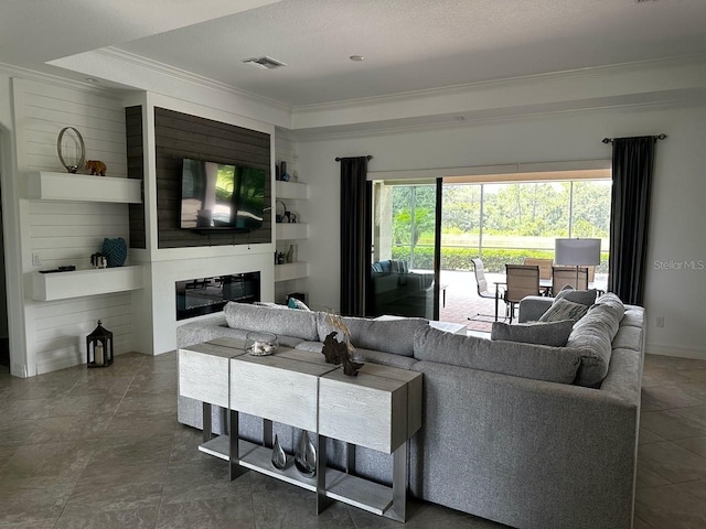 living room featuring built in shelves, a textured ceiling, a raised ceiling, and crown molding