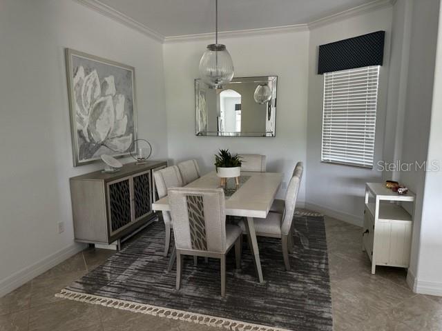 dining area with dark tile patterned floors and ornamental molding