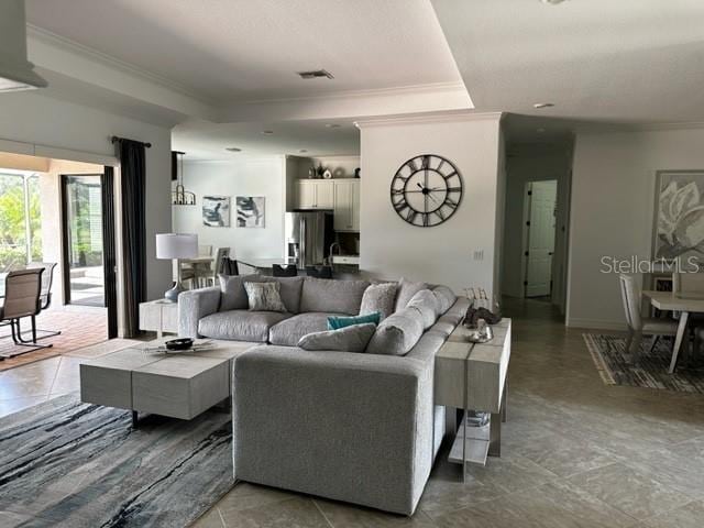 living room featuring a tray ceiling, crown molding, and tile patterned floors