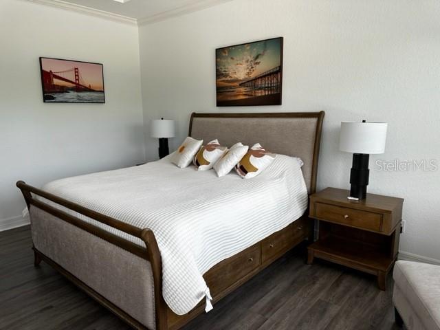 bedroom with dark wood-type flooring and crown molding