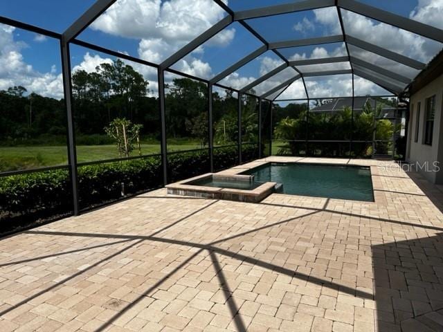 view of pool with a lanai, a patio area, and an in ground hot tub