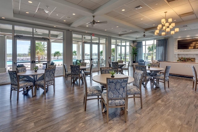 dining room featuring hardwood / wood-style flooring, ceiling fan with notable chandelier, a wall of windows, and french doors