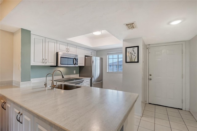 kitchen with kitchen peninsula, light tile flooring, sink, white cabinetry, and appliances with stainless steel finishes