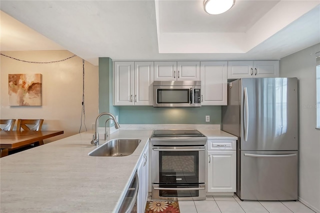 kitchen with white cabinets, light tile flooring, stainless steel appliances, a raised ceiling, and sink