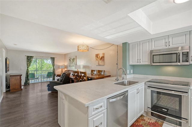 kitchen featuring dark hardwood / wood-style flooring, kitchen peninsula, stainless steel appliances, white cabinetry, and sink