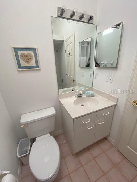 bathroom with tile floors, vanity with extensive cabinet space, and toilet