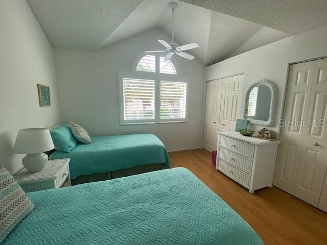 bedroom with multiple closets, lofted ceiling, and wood-type flooring