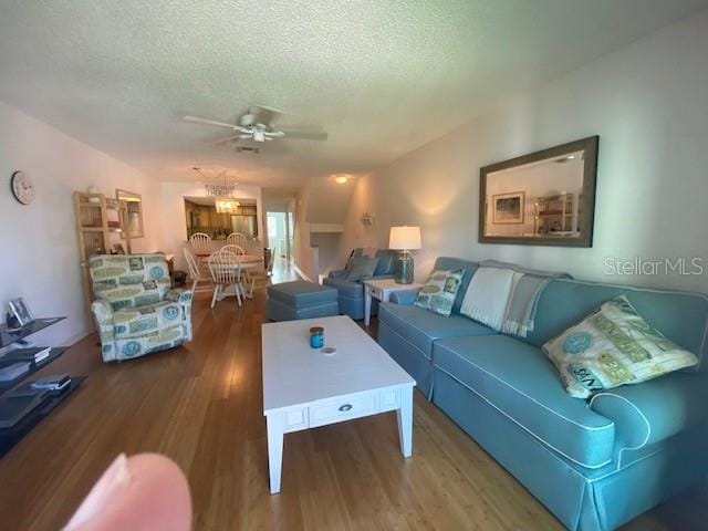 living room with a textured ceiling, ceiling fan, and wood finished floors