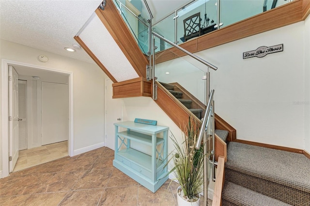 staircase with tile floors and a textured ceiling