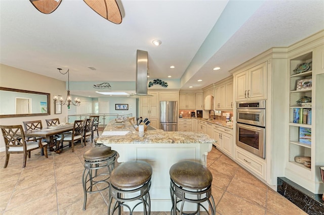 kitchen with cream cabinetry, appliances with stainless steel finishes, exhaust hood, sink, and light tile floors