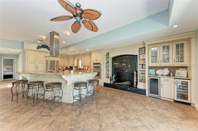 kitchen featuring a high end fireplace, cream cabinetry, extractor fan, wine cooler, and ceiling fan