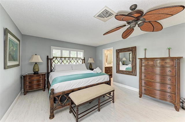 bedroom with ceiling fan, light hardwood / wood-style flooring, a textured ceiling, and connected bathroom