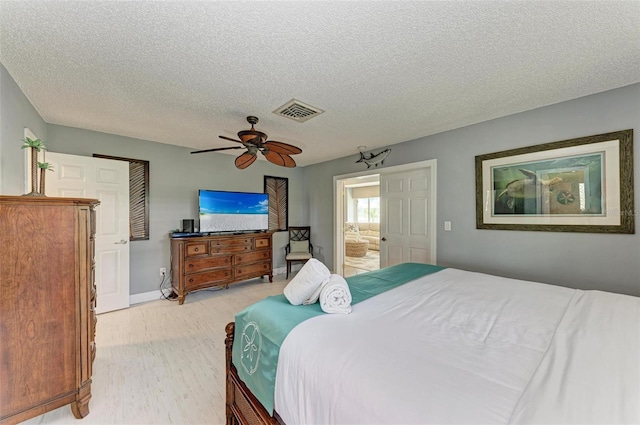 carpeted bedroom featuring ensuite bath, ceiling fan, and a textured ceiling