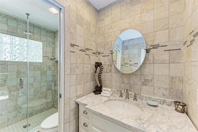 bathroom featuring tile walls, an enclosed shower, vanity, and toilet