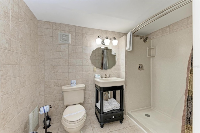 bathroom with tiled shower, tile walls, toilet, tile floors, and vanity