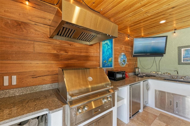 kitchen featuring stone counters, extractor fan, wood ceiling, sink, and wooden walls