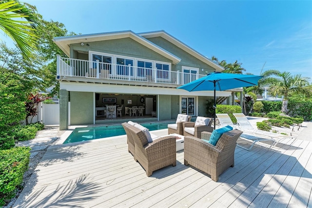 back of house with outdoor lounge area, a pool side deck, and a balcony