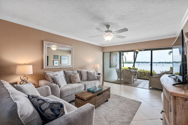 tiled living room featuring crown molding, a textured ceiling, ceiling fan, and a water view