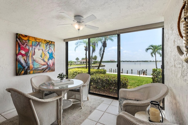 sunroom / solarium with ceiling fan and a water view