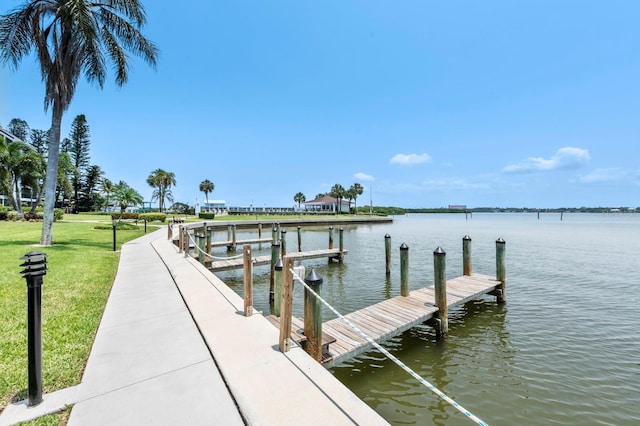 view of dock with a lawn and a water view