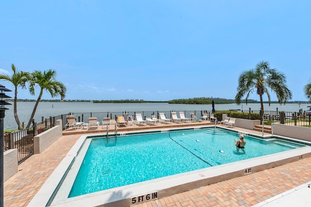 view of swimming pool featuring a water view and a patio area