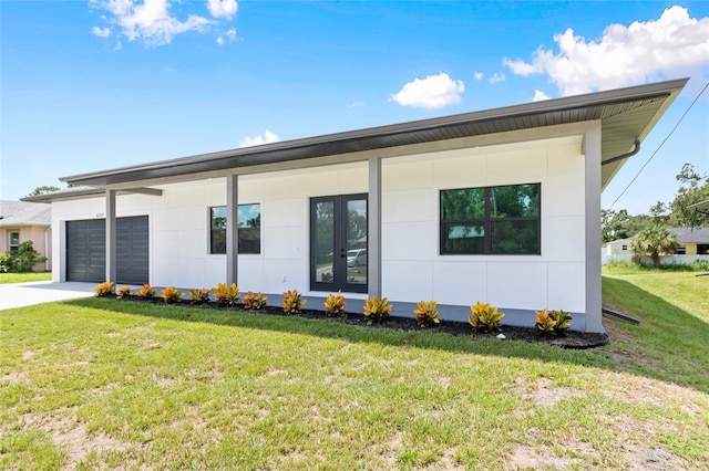 view of front of home with an attached garage, french doors, driveway, and a front yard