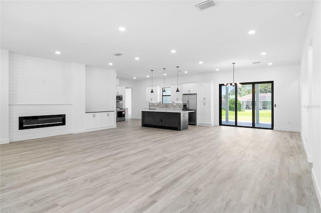 unfurnished living room featuring light wood-type flooring, visible vents, recessed lighting, and a fireplace