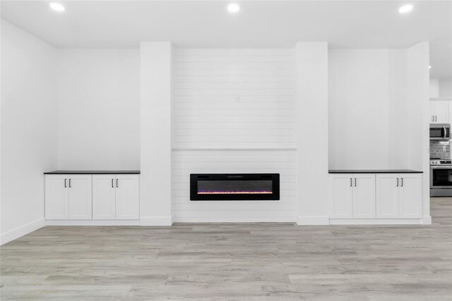 unfurnished living room with a fireplace and light wood-type flooring