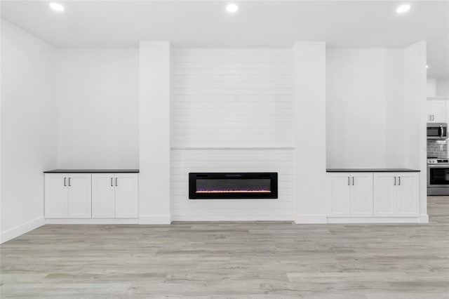 unfurnished living room with recessed lighting, light wood-style flooring, and a fireplace