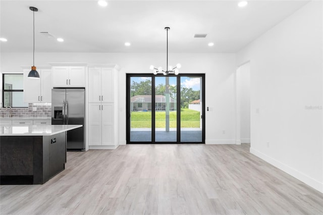 kitchen with light hardwood / wood-style floors, tasteful backsplash, fridge, and decorative light fixtures