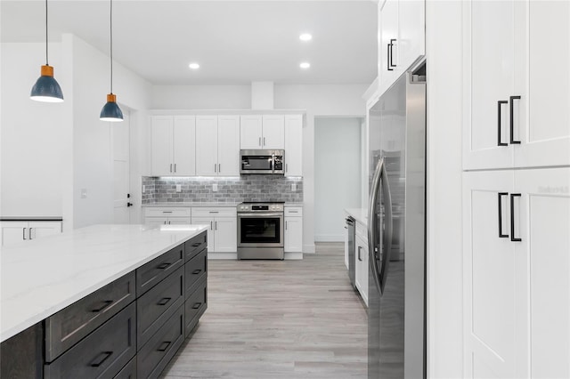 kitchen with pendant lighting, stainless steel appliances, white cabinets, decorative backsplash, and light stone countertops