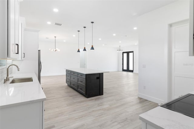 kitchen with sink, decorative light fixtures, light hardwood / wood-style floors, a kitchen island, and white cabinetry