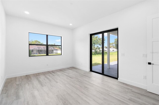 empty room featuring light wood-style flooring, recessed lighting, baseboards, and a wealth of natural light