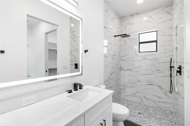 bathroom with toilet, a tile shower, and vanity