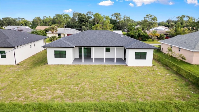 back of property featuring a lawn, a shingled roof, a patio, and fence