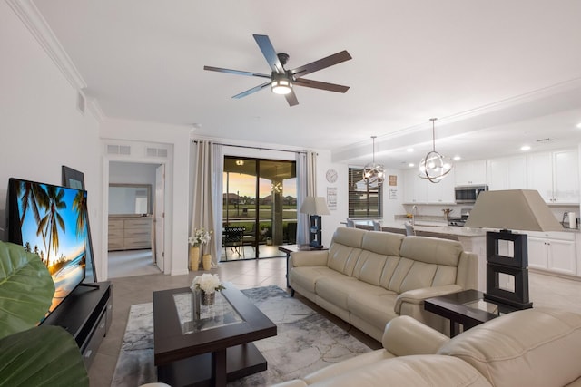 living room with sink, ornamental molding, light tile floors, and ceiling fan with notable chandelier